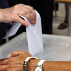 Detall d'un votant introduïnt la papereta en una urna