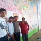 El Salamt, l'Ali, el Zaheer i l'Amjad somriuen al davant de la pintura que van elaborar junt amb els voluntaris.