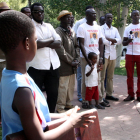 Pla general d'un grup de senegalesos i del germà de Mor Sylla sent entrevistat per una televisió senegalesa, amb un nen en primer terme, d'esquenes, l'11 d'agost a la plaça de la Pau de Salou