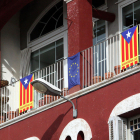 Banderas esteladas en un balcón, al lado de una bandera europea.