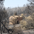 Un edificio abandonado con los efectos del incendio de la Ribera de Ebro al fondo entre la Palma y Vinebre