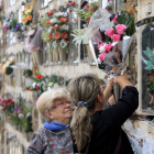 Imatge de dues dones posant flors al nínxol d'un familiar al cementiri de Montjuïc per Tots Sants.