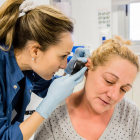 Una enfermera inspeccionando el interior de la oreja de una paciente.