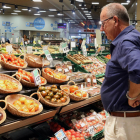 Un home compara els preus de la verdura en un supermercat de Barcelona.