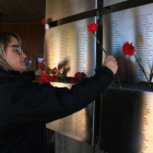 Una mujer coloca claveles en el Memorial de les Camposines de la Fatarella.