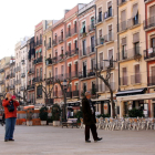 Un par de turistas paseando y haciendo fotos con el móvil en la plaça de la Font de Tarragona.