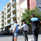 Agentes de la Guardia Urbana de Reus, en primer término, conversando con gitanos que han ocupado uno de los pisos, y encima de un balcón de las viviendas ocupadas, una mujer observándolos.