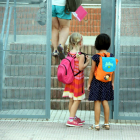Dues nenes d'esquema amb les motxilles a punt d'entrar a l'escola del Pinell de Brai en el segon dia de curs. Imatge del 13 de setembre de 2106 (horitzontal)