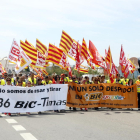 Plano general de los trabajadores de BIC Graphic en Tarragona, haciendo una marcha lenta encabezada por pancartas de protesta en la autovía de Salou, con el tráfico parado en el fondo. Imagen del 9 de mayo del 2017