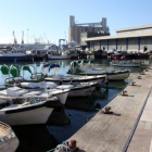 Barques de pescadors al barri del Serrallo de Tarragona, amb l'edifici de la Llotja de Peix al fons.