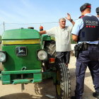 Plano general de dos agentes de los Mossos D'Esquadra conversando con un campesino al lado de su tractor en una masía de Vallmoll (Alt Camp), el 7 de julio del 2017