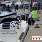 Uno agentes de los Mossos revisa una de las embarcaciones de los denunciados al puerto deportivo de Deltebre.