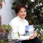 Maria Isabel en la entrada de su casa, con su primer libro, 'La Llama Fría y Cantos de Ausencias'.