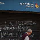 Un home passa per davant de la reixa de la seu de Gas Natural a Reus, acabada de pintar amb un grafit on s'hi llegeix "la pobresa energètica mata". Imatge del 19 de novembre de 2016