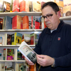 Pla mig d'Octavi Serret, enmig dels llibres del seu establiment de Vall-de-roures, fullejant un exemplar del 'Camí de Sirga' de Jesús Moncada. Imatge del 21 d'abril de 2017 (horitzontal)