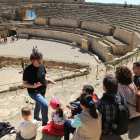 Pla obert de diversos turistes, d'esquena, gaudint d'una visita guiada a l'amfiteatre de Tarragona.