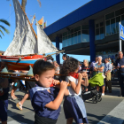 Uns nens vestits de pescadors porten un vaixell a espatlles.