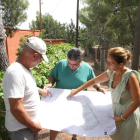 El Fausto, el Juan Antonio i l'Eva observen el mapa de distribució de les parcel·les a un dels camins per urbanitzar de la zona.