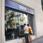 Imatge d'arxiu d'una parella davant d'un caixer automàtic del BBVA en un carrer de Barcelona.