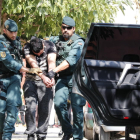 Imagen del chico detenido en Vinaròs, presuntamente relacionado con los atentados de Barcelona y Cambrils, mientras lo trasladan dos agentes de la Guardia Civil al vehículo policial.