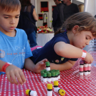 Pla mig de dos nens jugant a apilar taps com si siguin castells, durant la Fira Castells. Imatge del 21 d'octubre de 2017