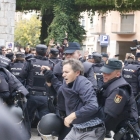 Dos policías se llevan a un hombre de la Escuela Bruguera de Girona.