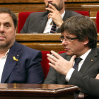 El presidente de la Generalitat, Carles Puigdemont, habla con el vicepresidente, Oriol Junqueras, en el Parlamento