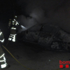 Imatge dels bombers mullant els vehicles cremats per evitar que proliferi el foc