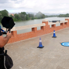 El piloto de drones de la Policía Local de Tortosa hace uso del aparato al lado del río Ebro, delante de uno de sus compañeros.