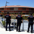 Plano general de tres agentes de la unidad ARRO de los Mossos D'Esquadra, de espaldas, en un punto estático de vigilancia en la Anilla Mediterránea de Tarragona, con el Palau de Deportes Cataluña en el fondo.