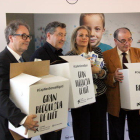 Marc Simón, Joan Roca, Marta Peris i Frederic Gómez Pardo agafant les caixes per la recollida de llet durant la presentació de la campanya 'Cap nen sense bigoti'.
