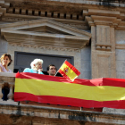 Unas personas exhiben una bandera española en un balcón.