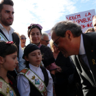 El president de la Generalitat, Quim Torra, rebut per dues nenes en la seva arribada al Centre Fluvial del Delta i amb pancartes al fons de protesta.