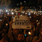 Un hombre sostiene una pancarta de 'Libertad Jordis' y, a su alrededor, personas con velas encendidas.