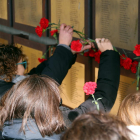 Alguns familiars dipositant clavells rojos sota les plaques que recorden les víctimes de la Guerra Civil al memorial de les Camposines.