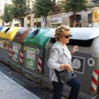 Una mujer que abre un contenedor de basua para tirar residuos.