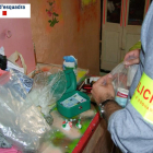 Un agente de los Mossos d'Esquadra inspeccionando las drogas y otros efectos intervenidos en un piso de Roquetes.