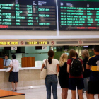 Imatge d'usuaris de Renfe fent cua a la guixeta d'informació sota el cartell de sortides i arribades a l'estació de Sants.