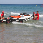 Los socorristas de la Cruz Roja entrando la moto acuática al agua, en la playa de l'Arrabassada de Tarragona.