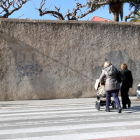 Imagen de unas seloras, de espalda, con un cochecito de niño pequeño, atravesando un paso de peatones en el centro de Valls, en un punto donde se quiere renovar el alumbrado