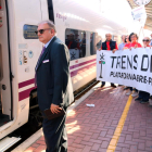 El revisor de l'Euromed a l'estació de l'Aldea davant la pancarta que sostenen activistes de Trens Dignes.