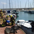 Bomberos actuando en el puerto de Torredembarra delante de la embarcación que ha quemado.