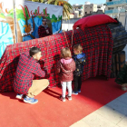 Dos nens fan cagar un tió de grans dimensions a la plaça dels Infants.