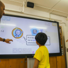 Moncusí explica a dos alumnes el funcionament d'un panel interactiu que ha incorporat l'escola.