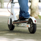 Primer plano de unos pies sobre un patinete eléctrico.