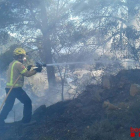 Un bomber amb la mànega treballant a l'incendi.