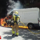 Imagen de un Bombero trabajando para apagar la furgoneta incendiada.