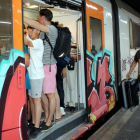 Pla general d'una porta d'un tren de Rodalies aturat a l'estació de Sants, amb els vagons plens de gent.