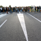 Primer pla de les senyals a l'asfalt de l'AP-7 a l'Ampolla amb els manifestants al fons. Imatge del 18 d'octubre del 2019 (vertical)