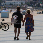 Dos turistas de espalda paseando por el paseo marítimo de Torredembarra.